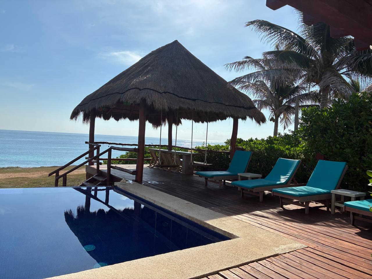 Alberca, palapa y mar Caribe